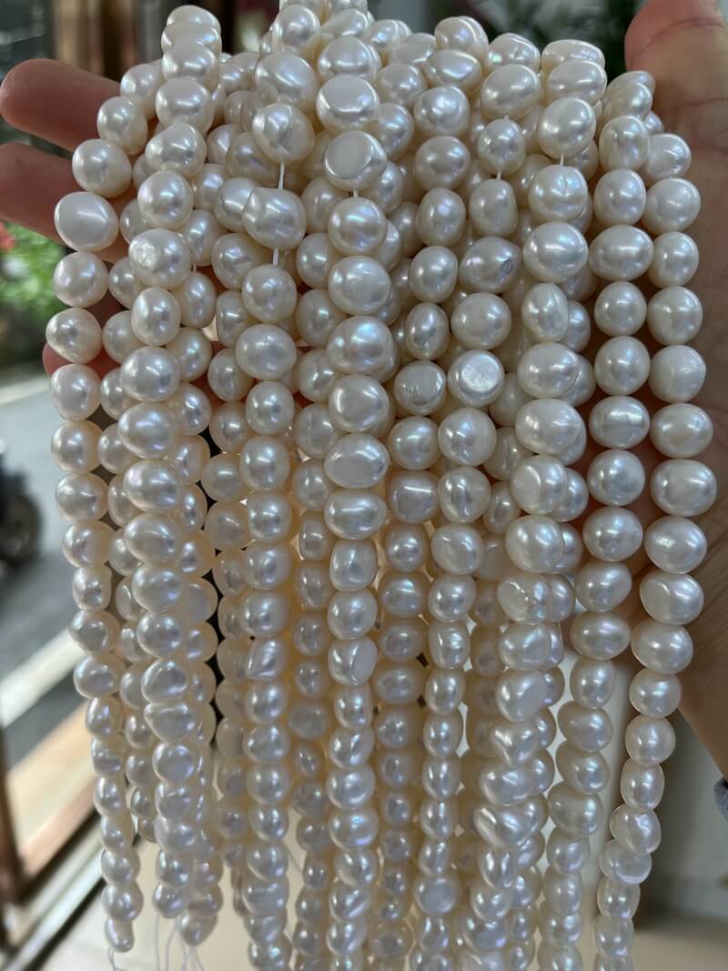 Close-up shot of natural white nugget-shaped freshwater pearls showcasing high luster and organic surfaces.