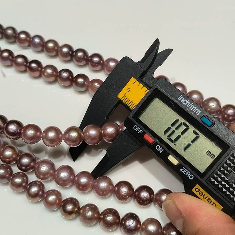 Caliper measurement of 10-11mm affordable dark Edison pearl strands showing near round shape.
