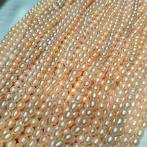 A loose peach pink oval pearl necklace strand showing drill holes ready for studio workshop assembly