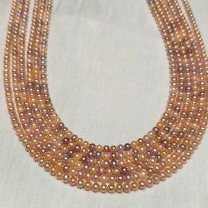 Five wholesale strands of premium baby pearls showcasing a lustrous mix of natural champagne, lavender, and peach tones.