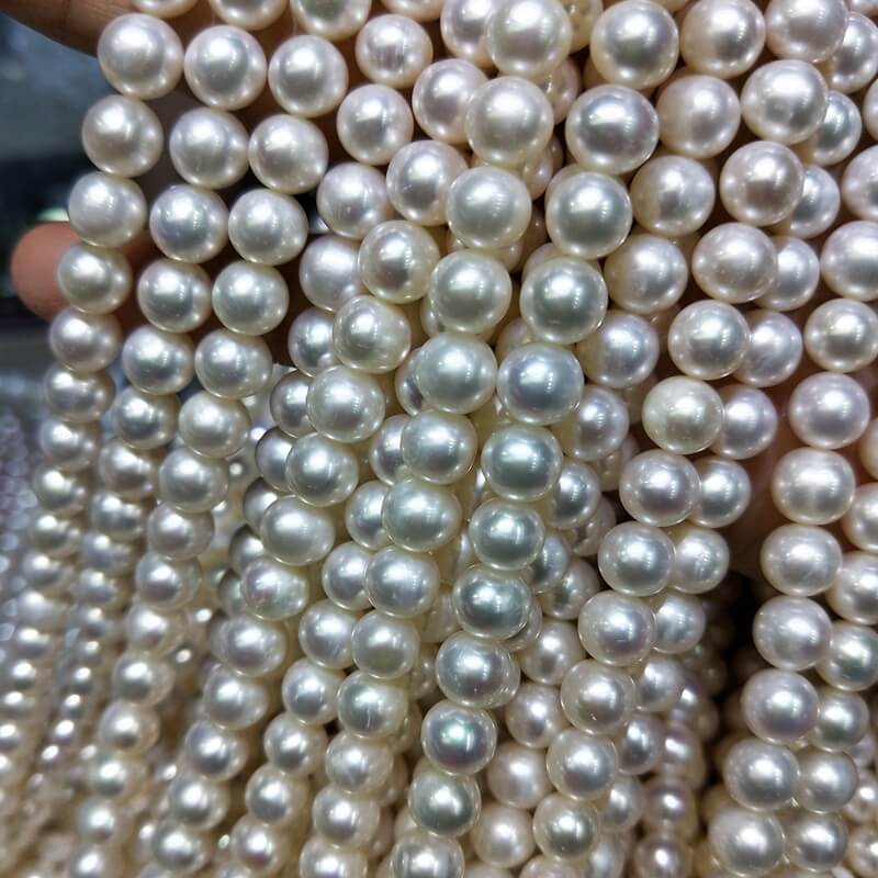 A bulk handful of 16-inch, high luster 8mm white freshwater pearl strands for necklaces, offered at wholesale factory price for jewelry manufacturers.