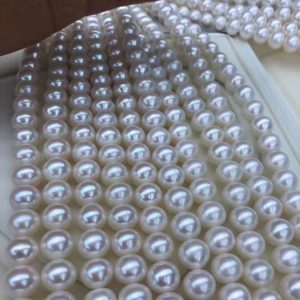 A bulk lot of 9-10mm high luster white freshwater pearl beads in loose strands for jewelry making.