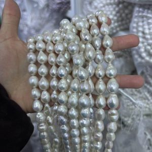 Handheld view of unclasped freshwater baroque teardrop pearl strands showing organic shape and thickness for B2B buyers.