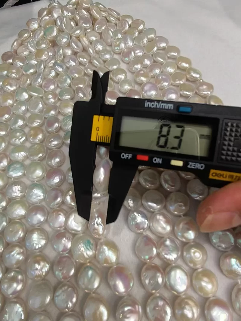 Precision center full-drilled white coin pearls with clean 0.8mm holes ready for wire wrapping assembly.