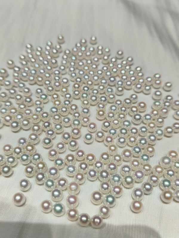 Loupe close-up showing a perfectly centered 0.7mm half-drilled hole on a 4.5mm white round pearl.