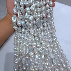 Wholesale strand of natural white fireball pearls in baroque shape, with a digital caliper measuring one pearl at 17.0mm width, ready for creating large statement giant pearl earrings.