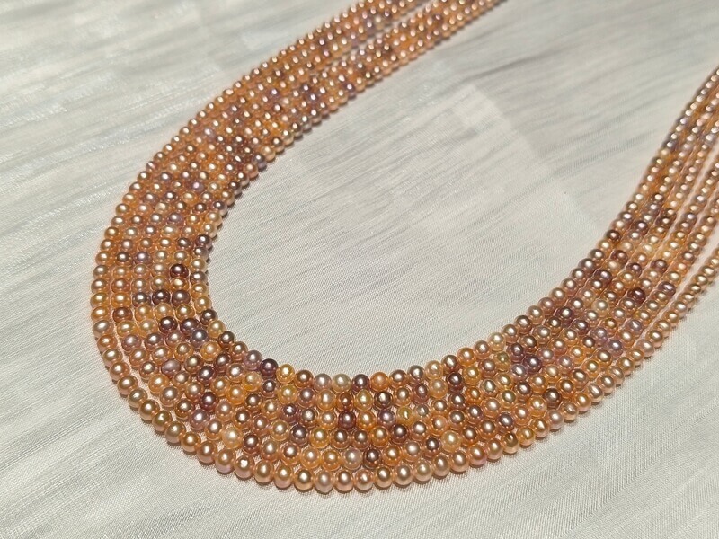 Close-up of dainty multicolor freshwater pearls in bulk with clean surfaces and brilliant mirror reflection for jewelry makers.