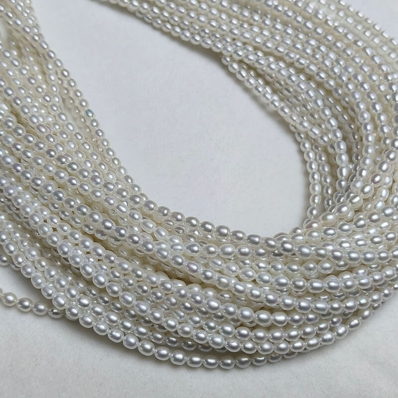 Premium real pearl necklace strands featuring 3-4mm white rice freshwater pearls with brilliant smooth luster for wholesale jewelry brands.