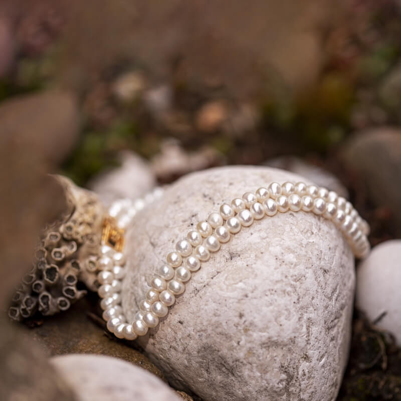 Double strand white freshwater cultured pearl necklace displayed on a natural stone, premium loose pearl wholesale.