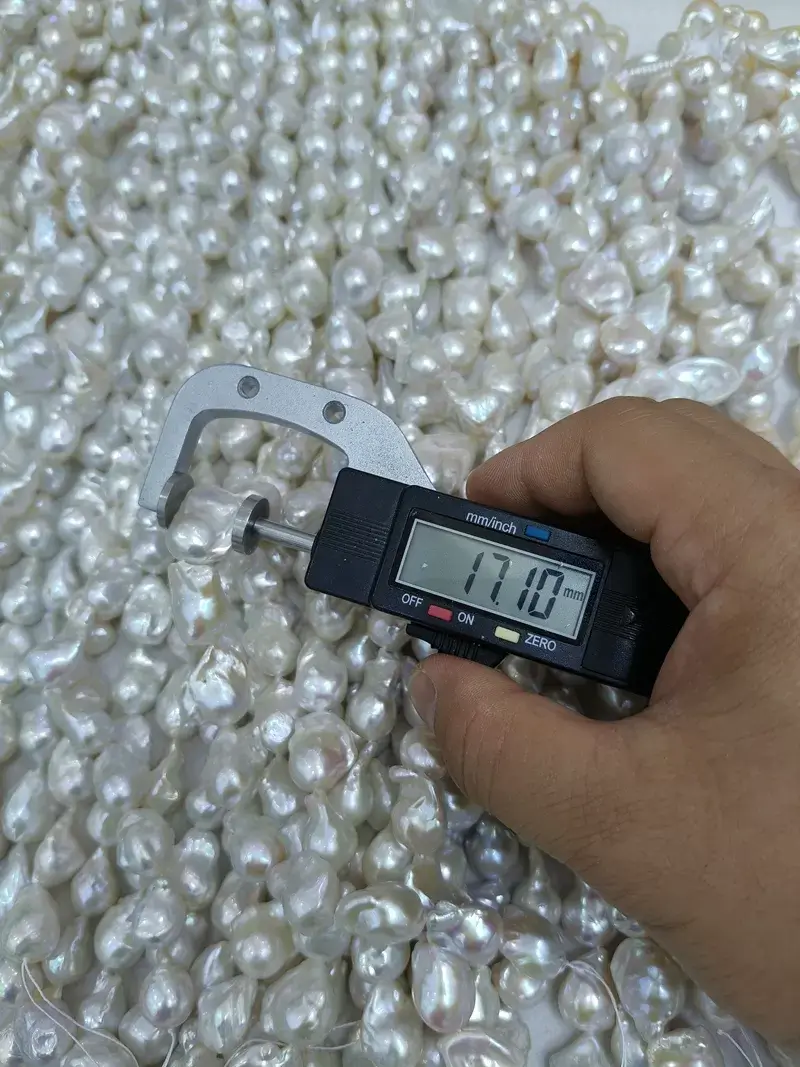 A digital caliper measuring a large 17.10mm white fireball baroque pearl jewelry strand, showcasing excellent mirror luster and unique sculptural forms for high-end necklace crafting.