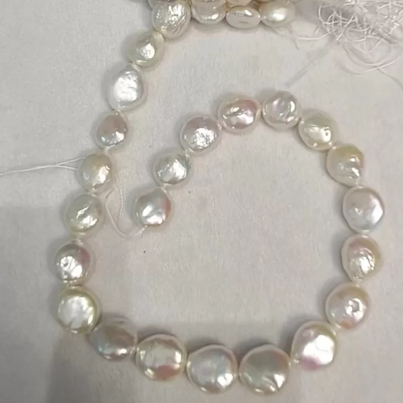 Close-up of premium 14mm flat disk white coin pearls with intense natural mirror luster and thick nacre.