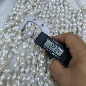 Longitudinal measurement of a 22.34mm bead-nucleated fireball pearl on a temporary 16 inch loose strand, perfect raw material for bespoke statement earrings and custom jewelry collections.
