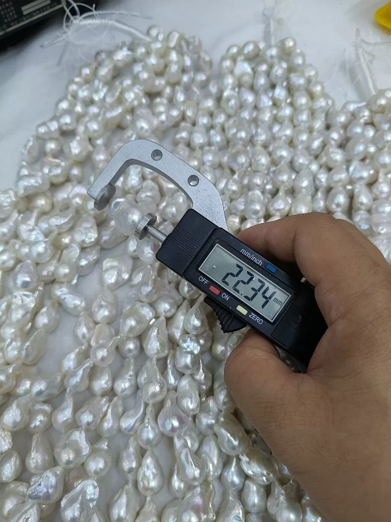 Longitudinal measurement of a 22.34mm bead-nucleated fireball pearl on a temporary 16 inch loose strand, perfect raw material for bespoke statement earrings and custom jewelry collections.