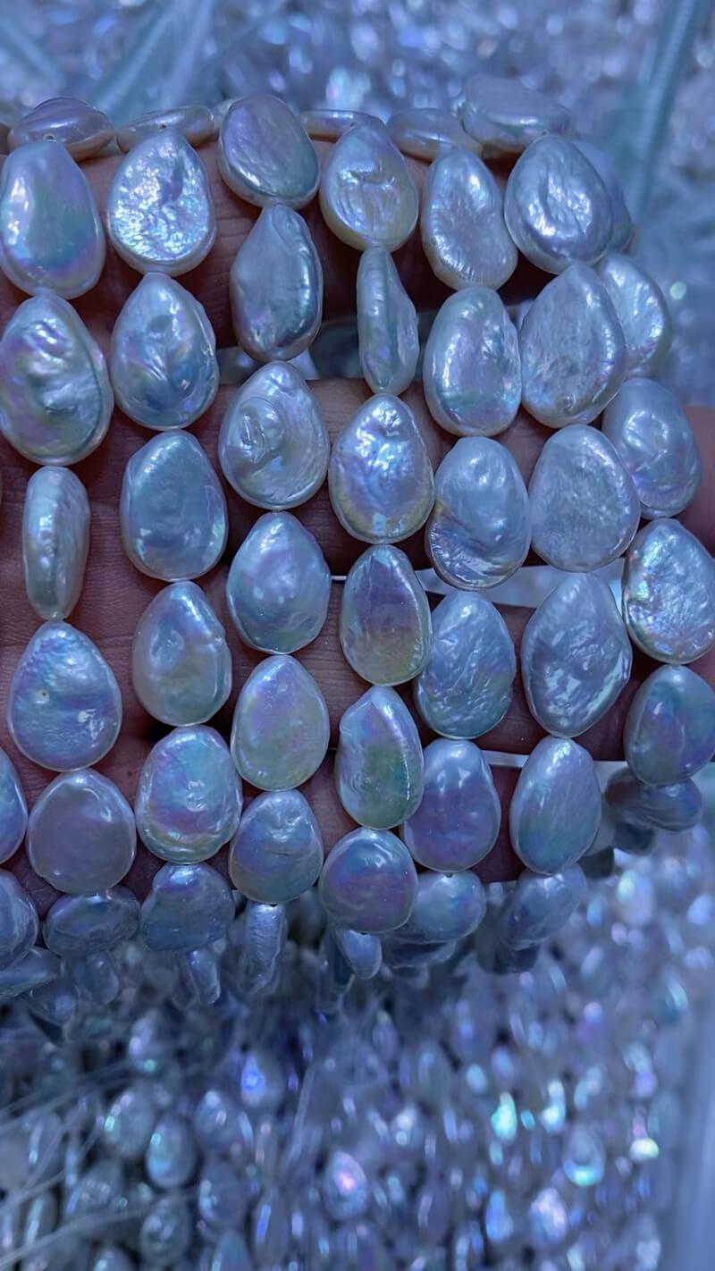 Top-drilled 9x12mm flat teardrop baroque pearl strands showing strong iridescence for DIY jewelry brands.