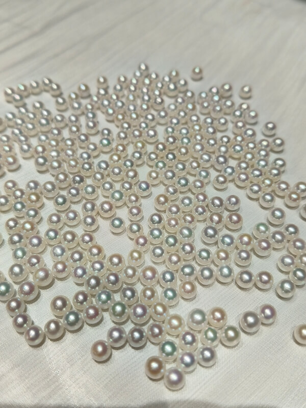 A bulk pile of high luster 4.5mm to 5mm round freshwater half-drilled pearls for jewelry making supply.