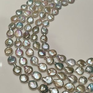 Close-up of flat round baroque coin pearls in bulk showcasing smooth surfaces and mirror-like pink-green orient.