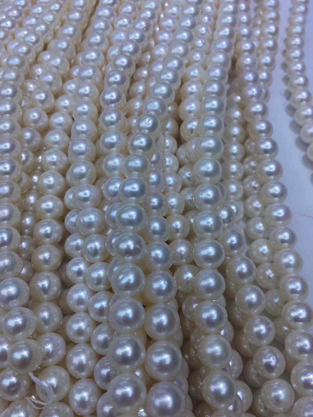 Natural white freshwater loose pearl strands arranged on a designer worktable for DIY bridal necklace making.