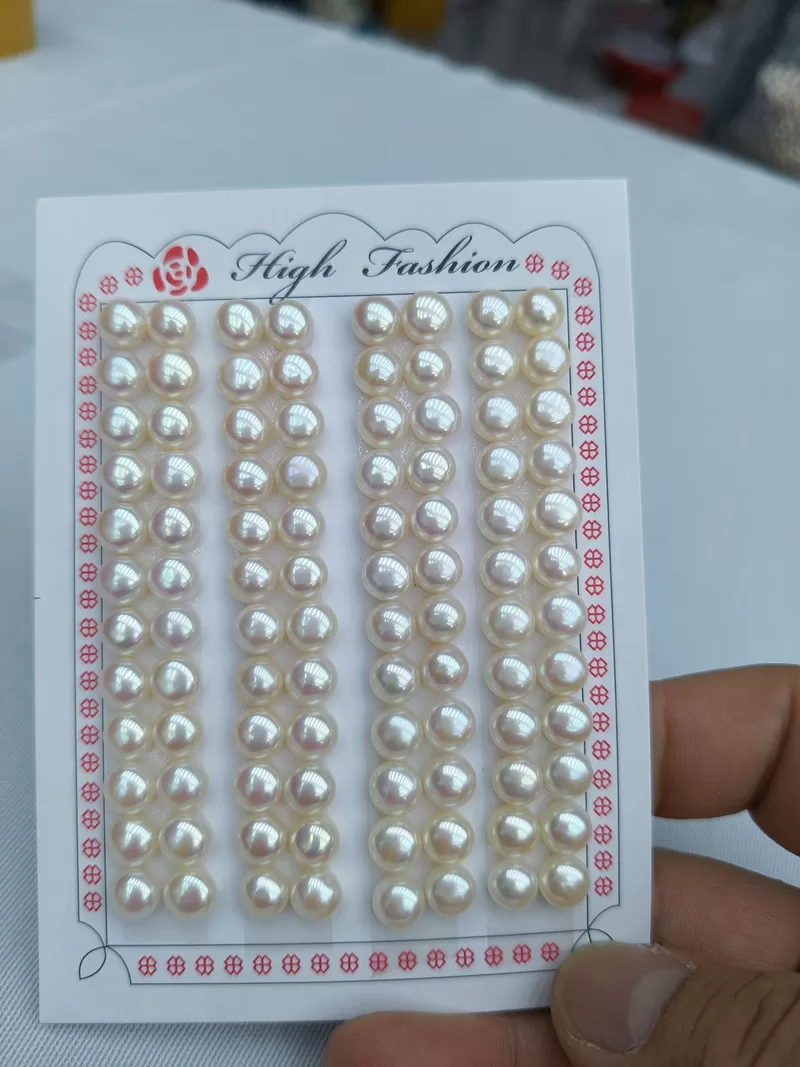 A finished pair of elegant pearl wedding earrings featuring the same high-luster, 7mm natural white freshwater button pearls shown on the wholesale display card.