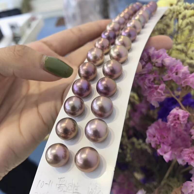 Real size comparison of round 10mm to 11mm deep purple Edison pearls on hand