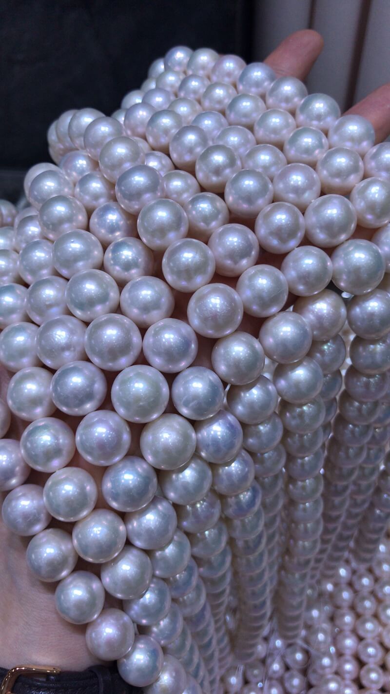 Close-up of near-round 11.0mm-12.0mm nucleated freshwater pearls, showcasing brilliant silver-pink iridescent radiant overtones and clean surfaces.