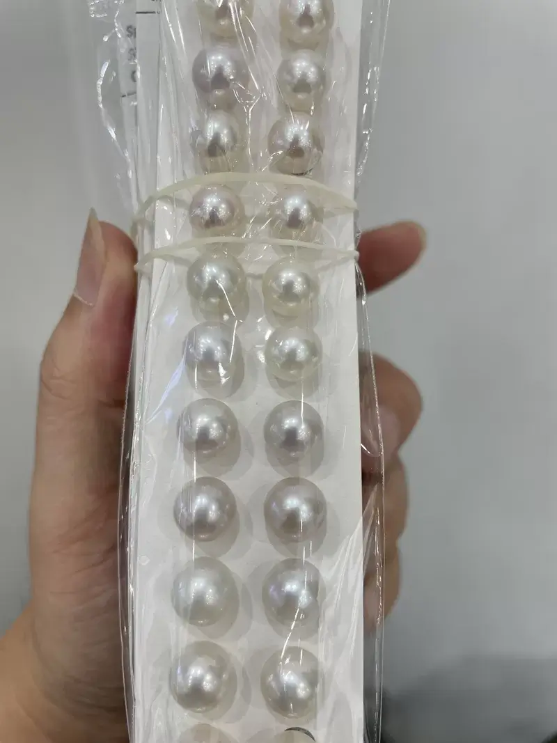 Handheld view of undrilled 9-10mm loose freshwater pearls showing round shape and size