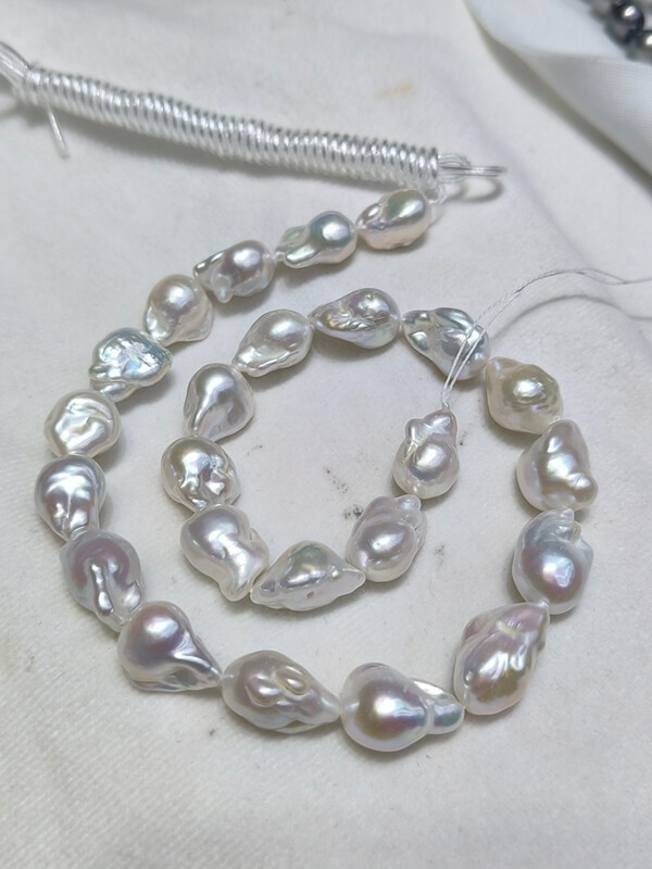 Wholesale 13-15mm plump white baroque pearl strand with high luster and uniform sizing for statement necklaces.