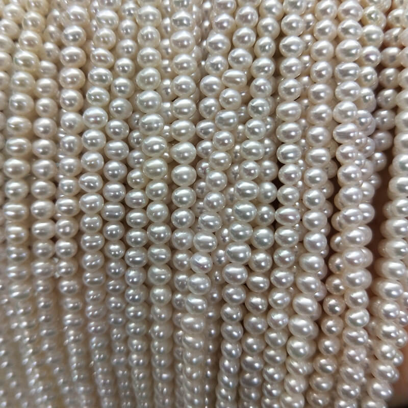 Multiple strands of wholesale 4mm small white potato freshwater pearls, high luster base material for designer jewelry making.