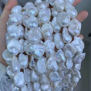 A hand holding large 16-inch wholesale chunky white baroque pearl strands with high luster, perfect for creating designer pearl necklaces.
