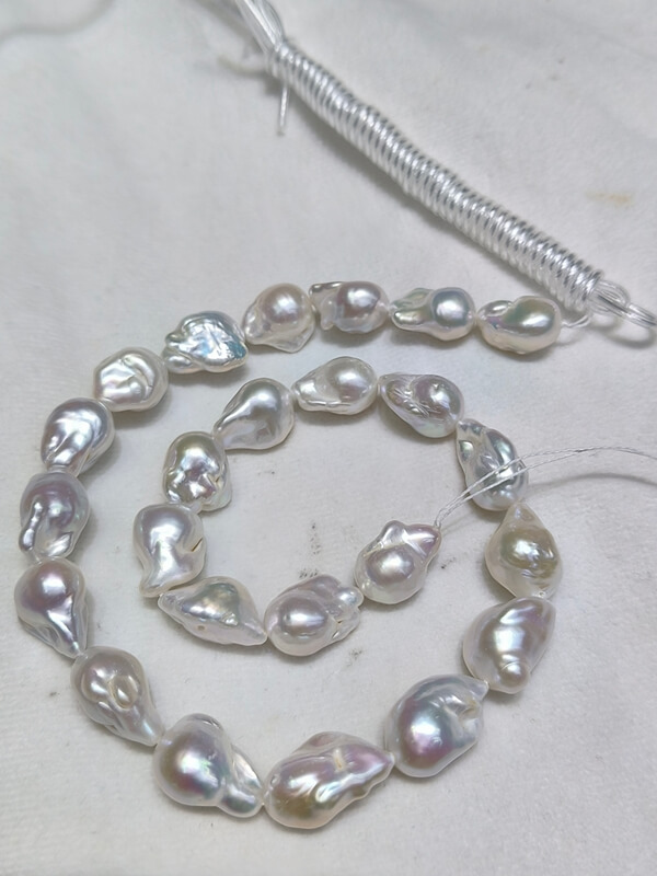 Oversized 20-25mm length natural white organic baroque pearls on a strand with strong metallic rainbow orient.