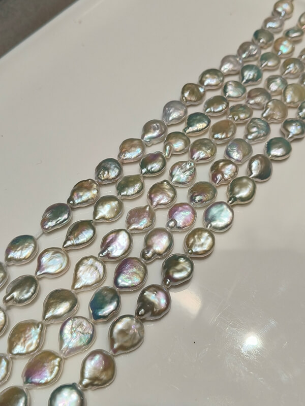 Four wholesale strands of premium disc baroque pearls displaying intense natural metallic rainbow luster.